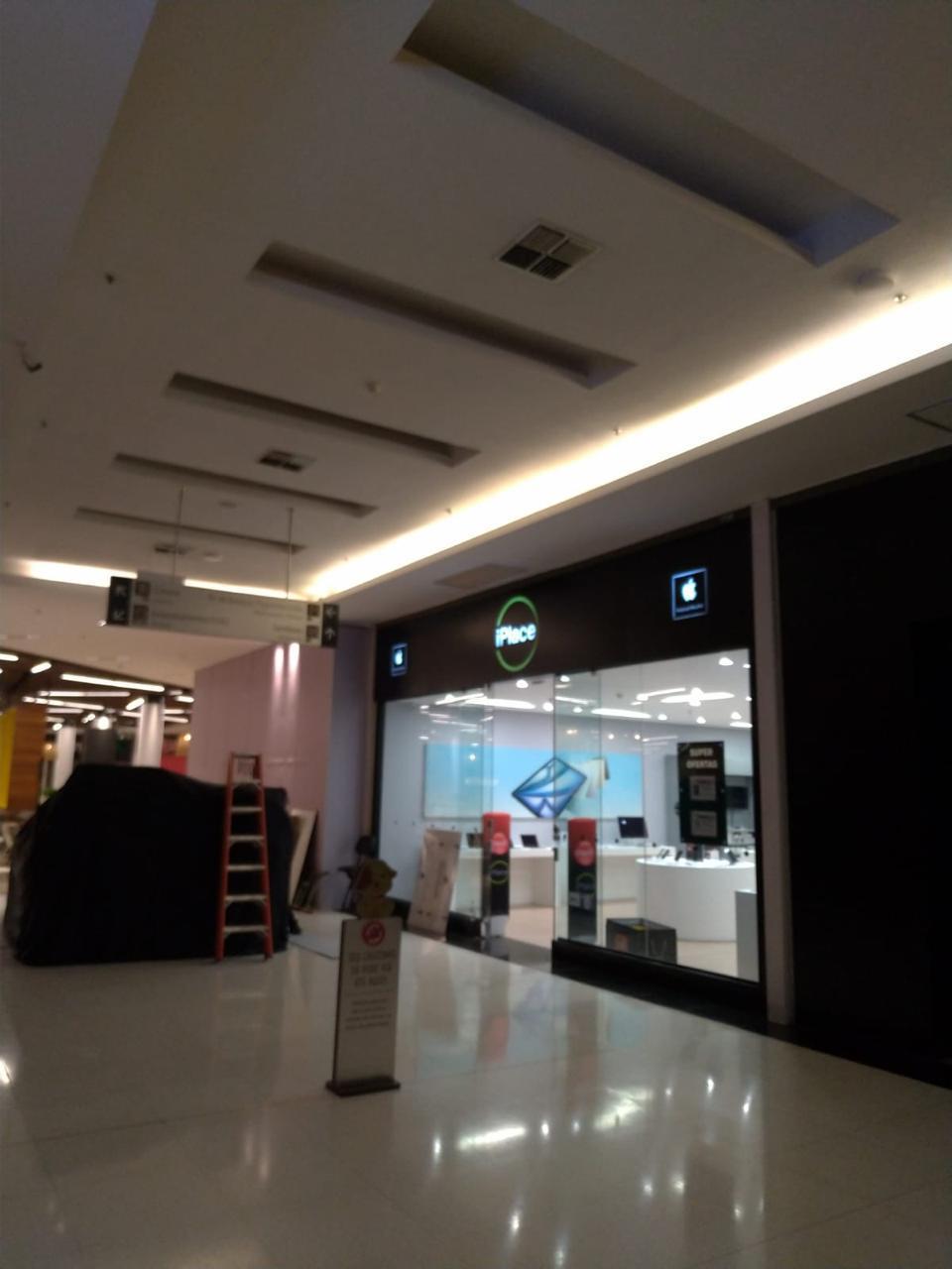 Fachada iluminada da iPlace vista do corredor do shopping