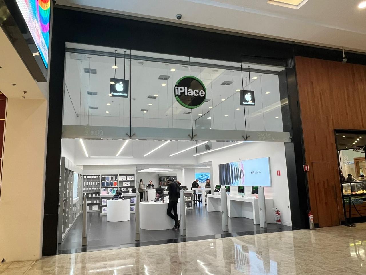 Fachada de vidro com luminoso circular da iPlace em shopping